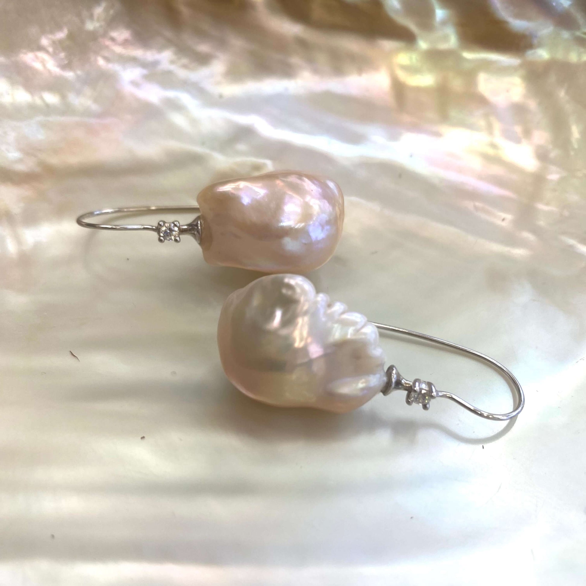 Golden Baroque Pearl Earrings – close-up against white pearl shell backdrop