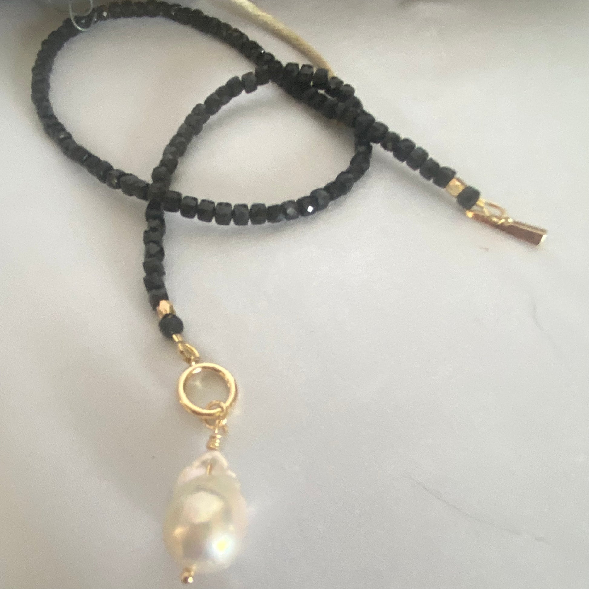 Black Tourmaline choker necklace with pearl charm, featuring sparkling faceted cube beads and a gold clasp.