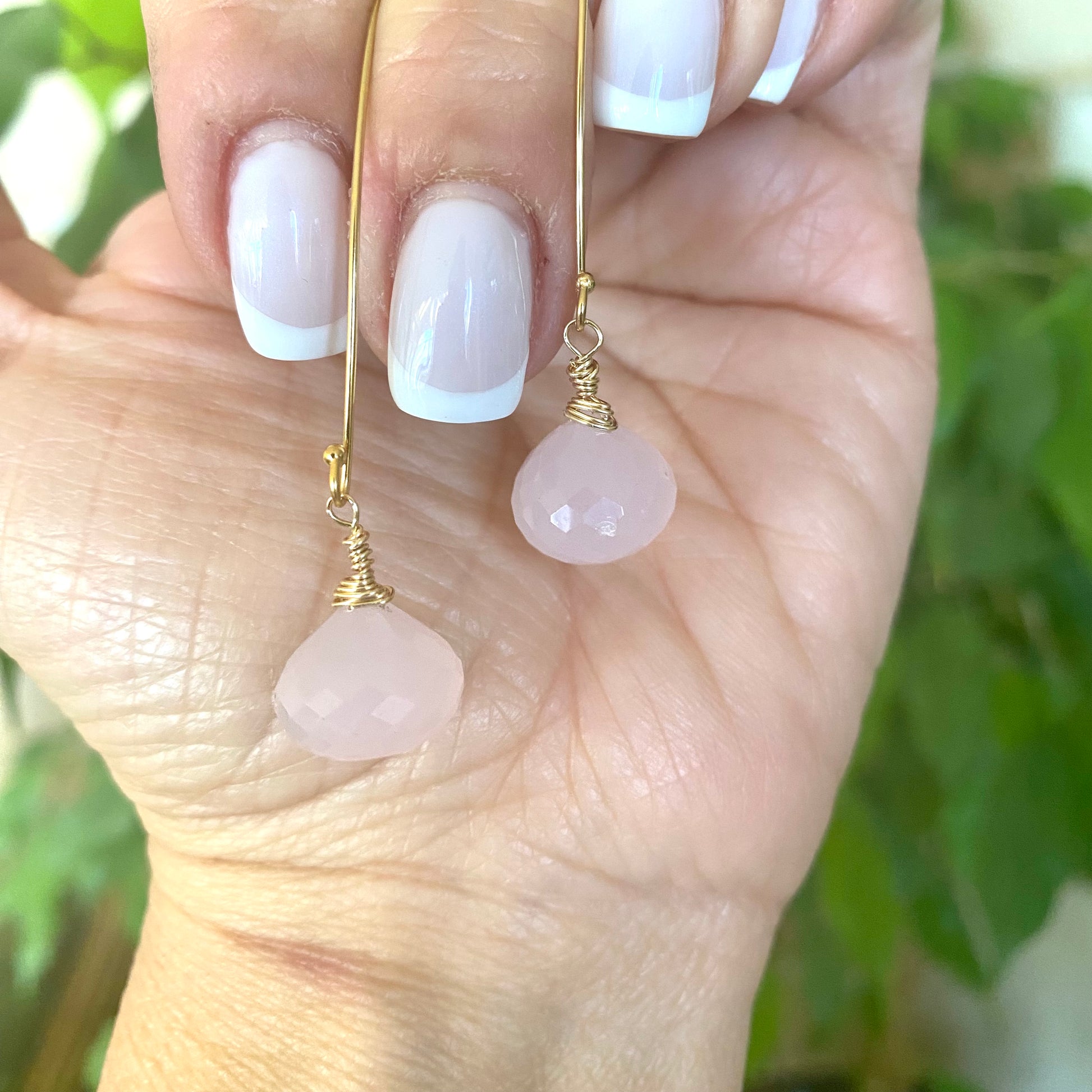 Rose quartz threader earrings with briolettes held in hand, showcasing blush-pink color and elegant design.