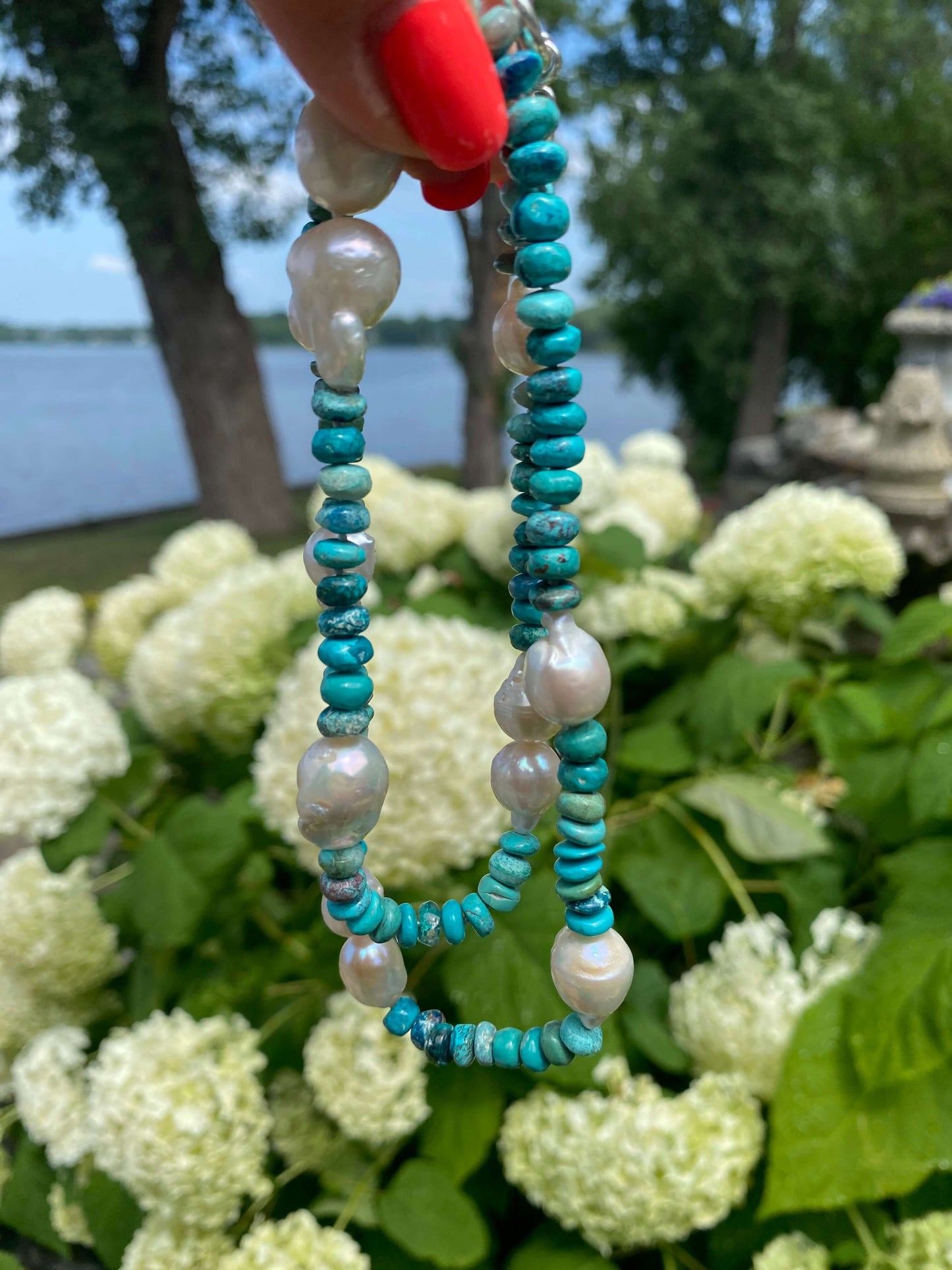 Arizona turquoise pearl necklace featuring turquoise rondelle beads and pearls set against lush greenery.
