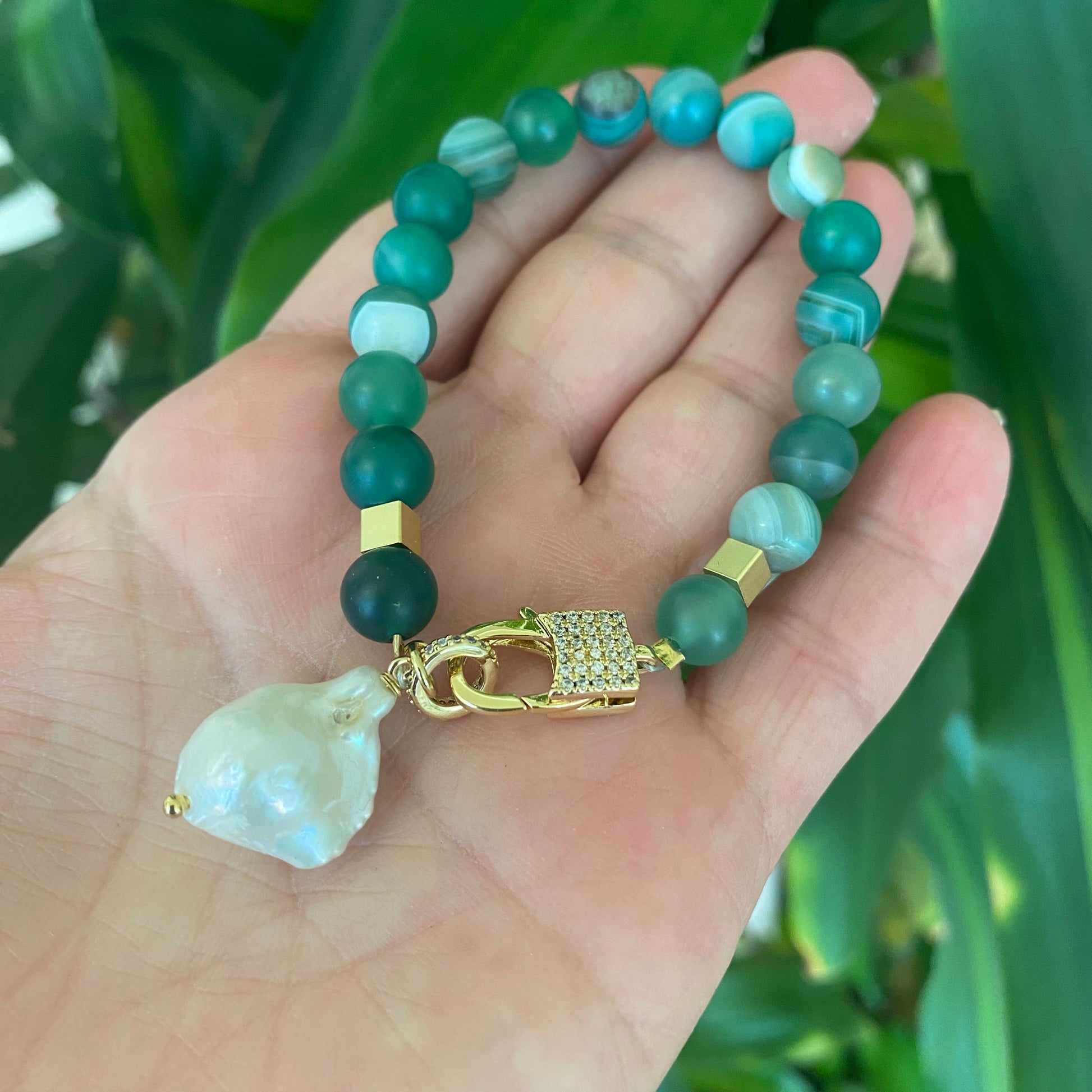 Sardonyx baroque pearl bracelet with green beads and gold plated clasp held in hand