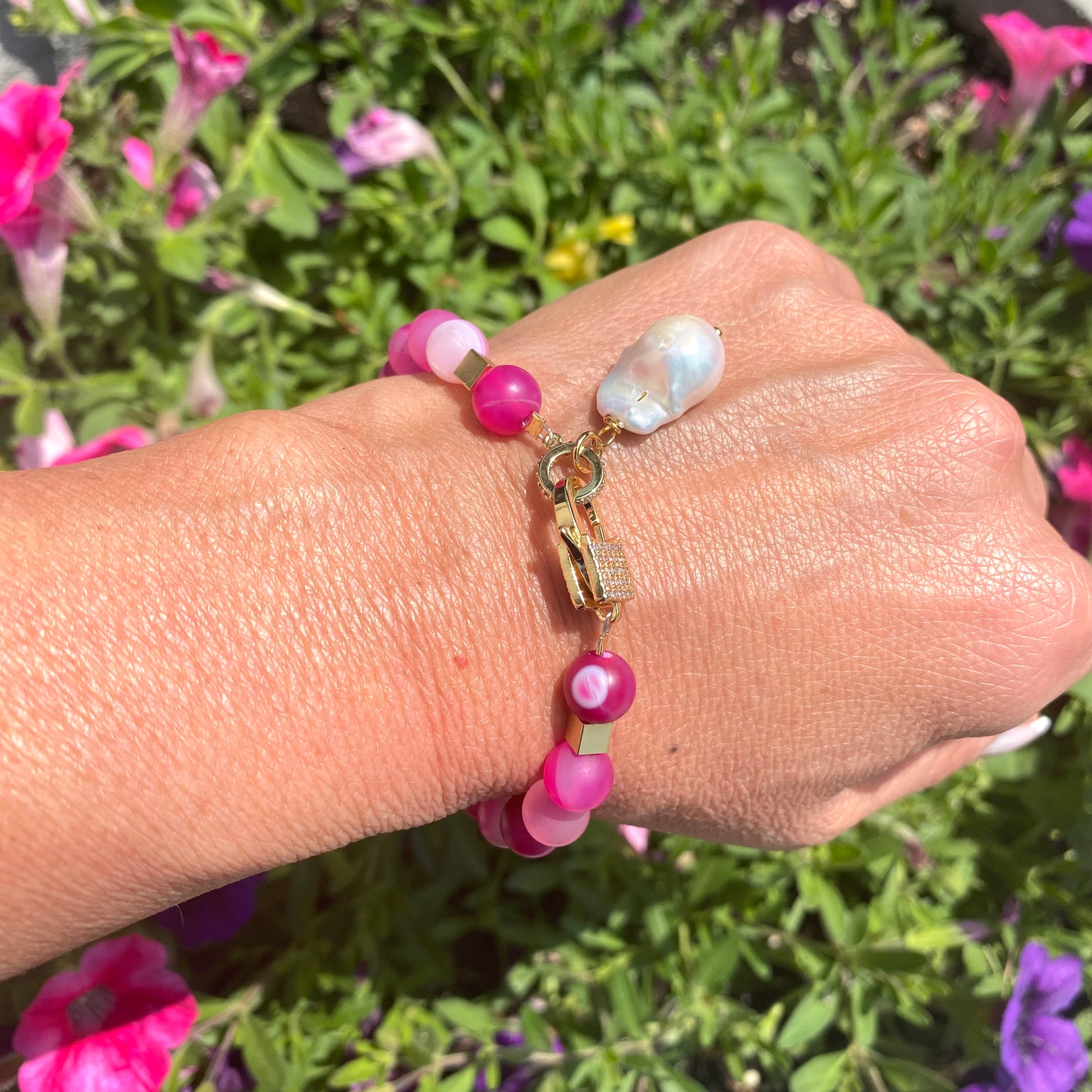 Sardonyx baroque pearl bracelet with hot pink beads styled outdoors on wrist