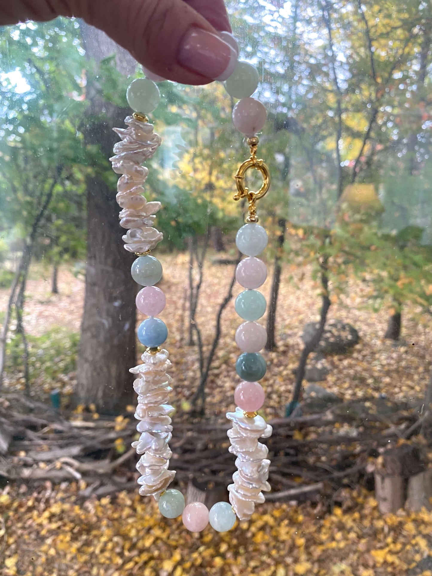 Aquamarine Morganite Necklace – held by hand against green foliage backdrop