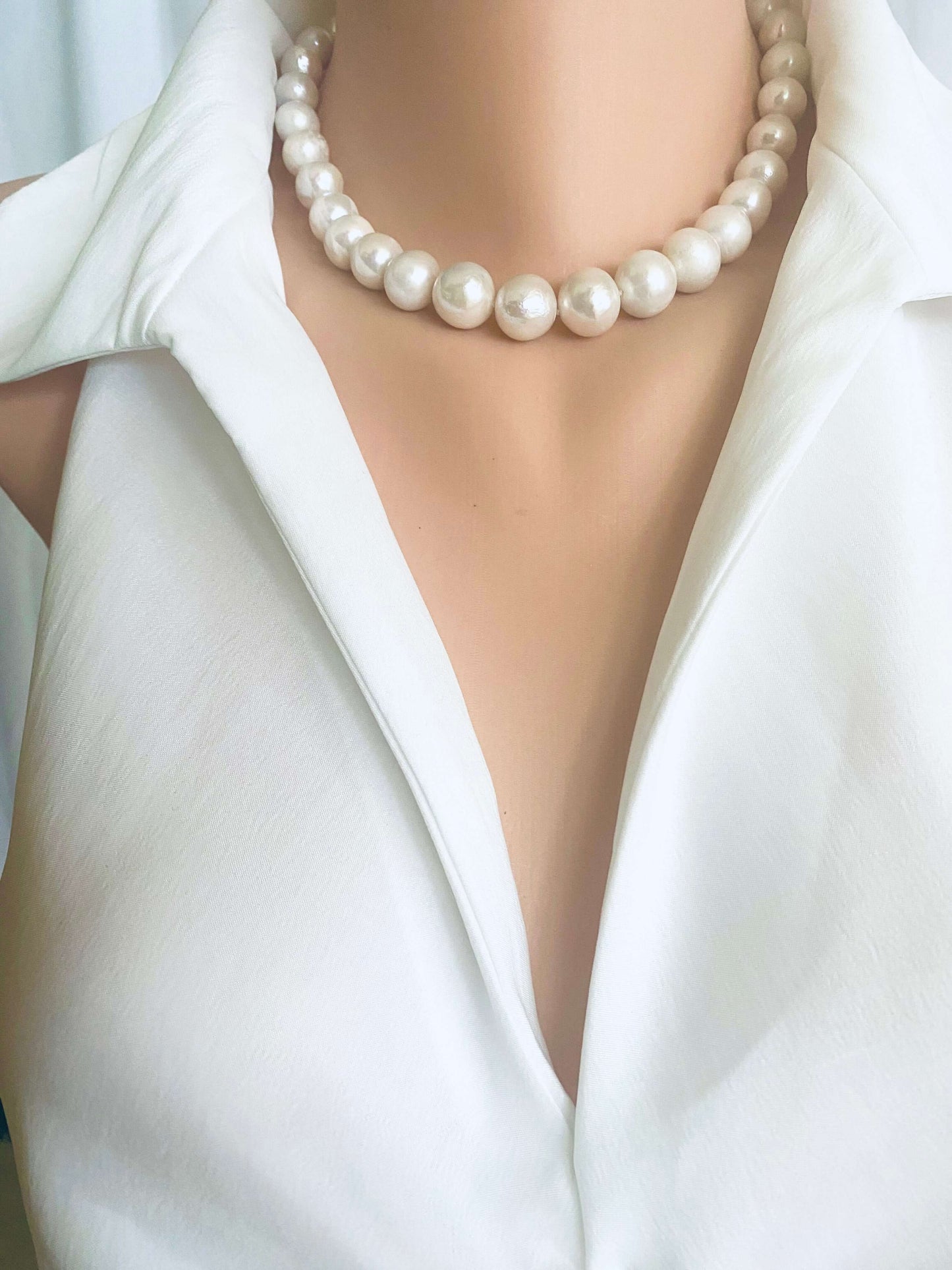 White Edison pearl necklace with large luminous pearls showcased on a mannequin wearing a white collared shirt.