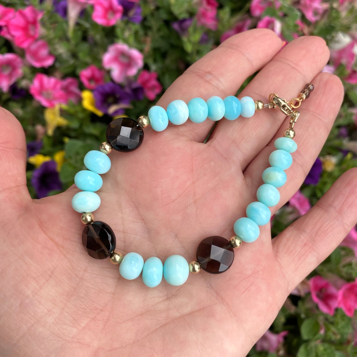 Opal quartz bracelet featuring sky blue opal and smoky quartz, showcasing unique design and craftsmanship in a floral background.