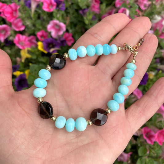 Opal quartz bracelet featuring sky blue opal and smoky quartz, showcasing unique design and craftsmanship in a floral background.