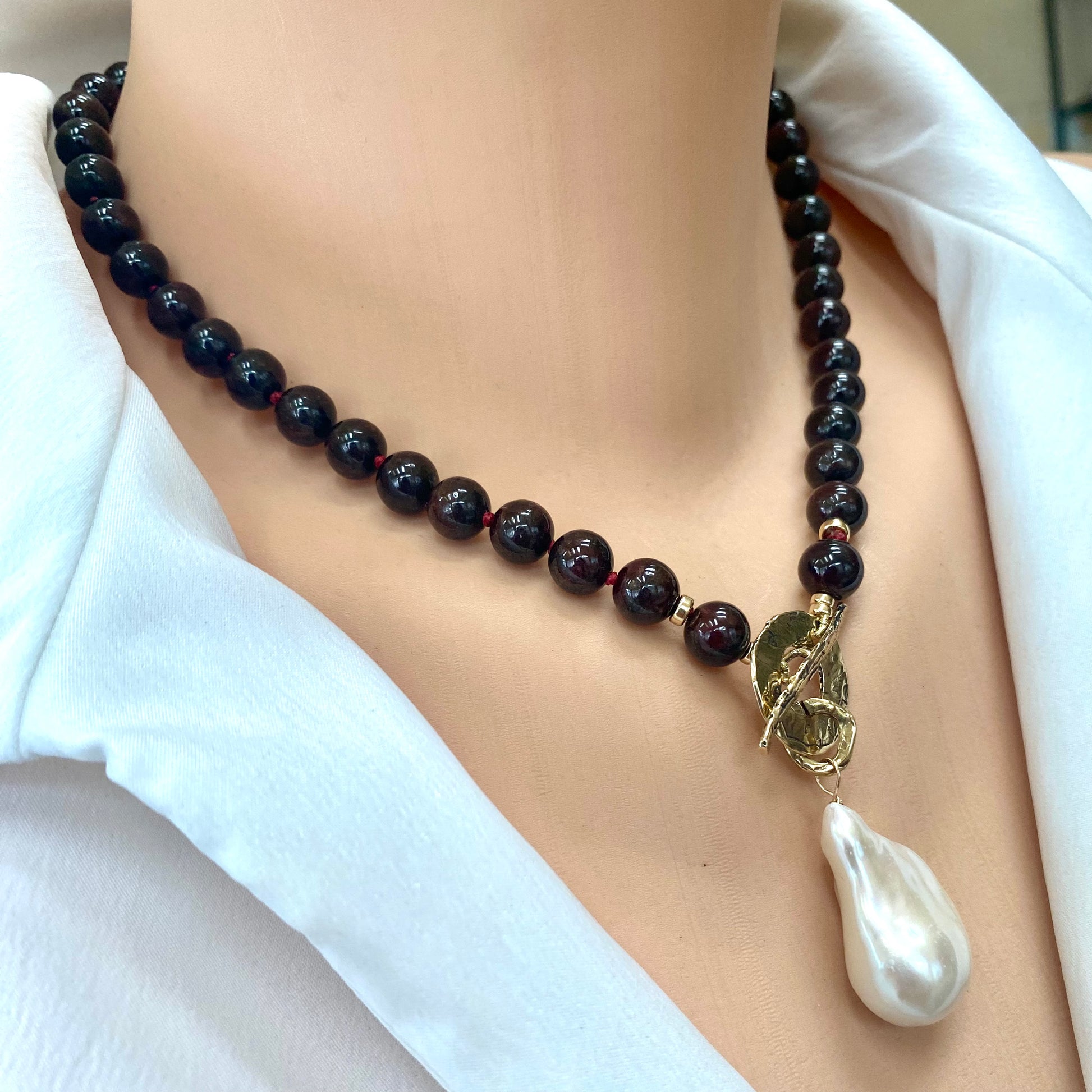 Garnet pearl necklace close up showing faceted garnet beads and white baroque pearl