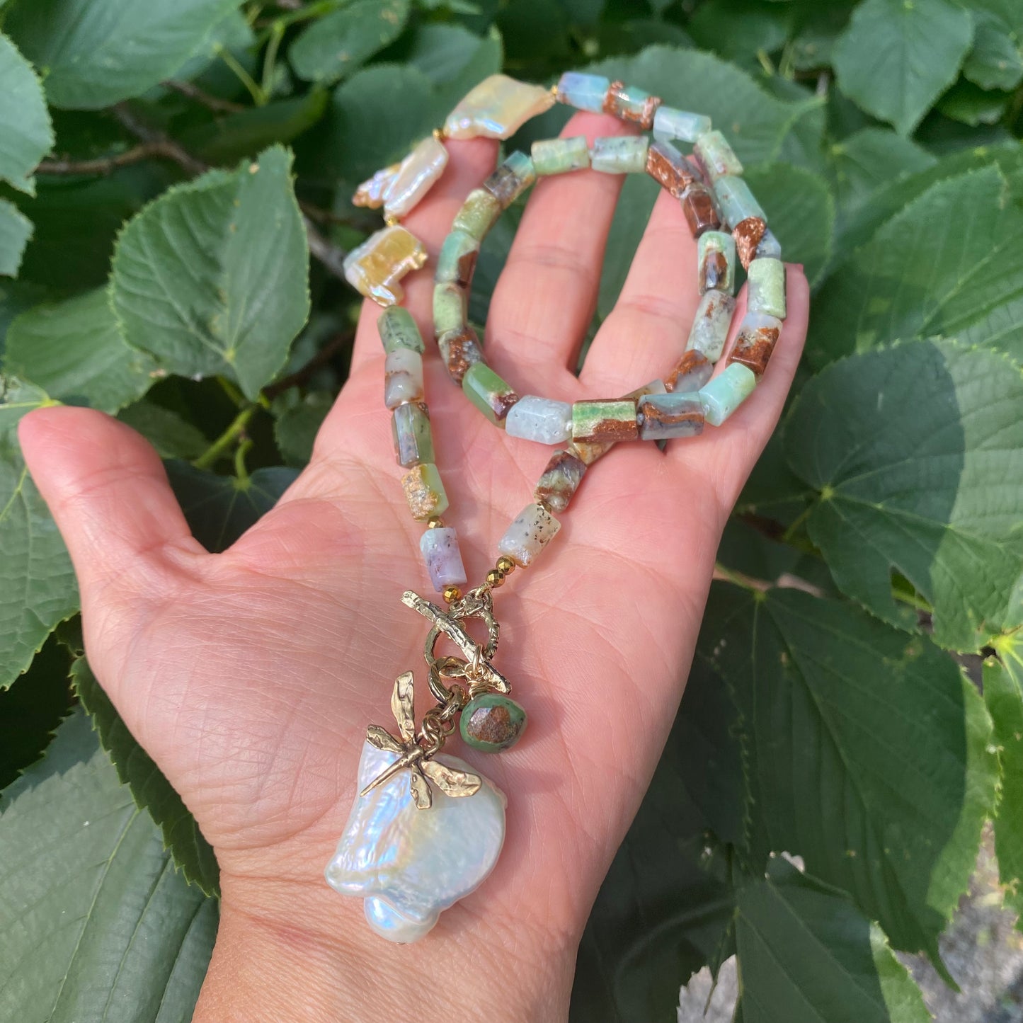 Chrysoprase necklace with dragonfly charm and baroque pearl, showcasing vibrant green gemstones in a beautiful design.