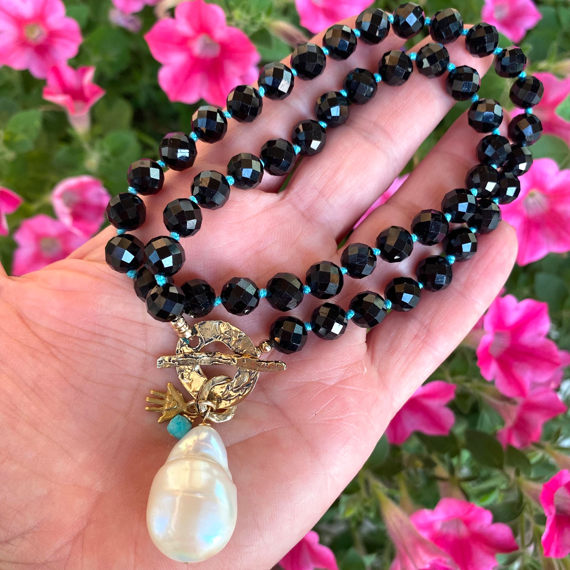 Black tourmaline baroque pearl toggle necklace held in hand showing faceted beads and pearl drop