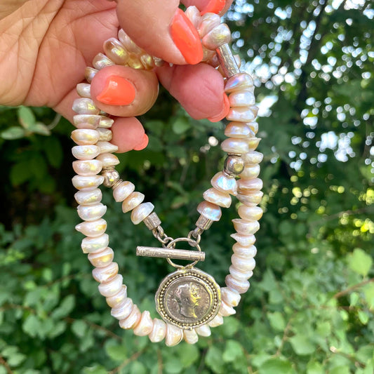 Lavender baroque pearl necklace featuring silver Roman coin toggle clasp in a natural setting.