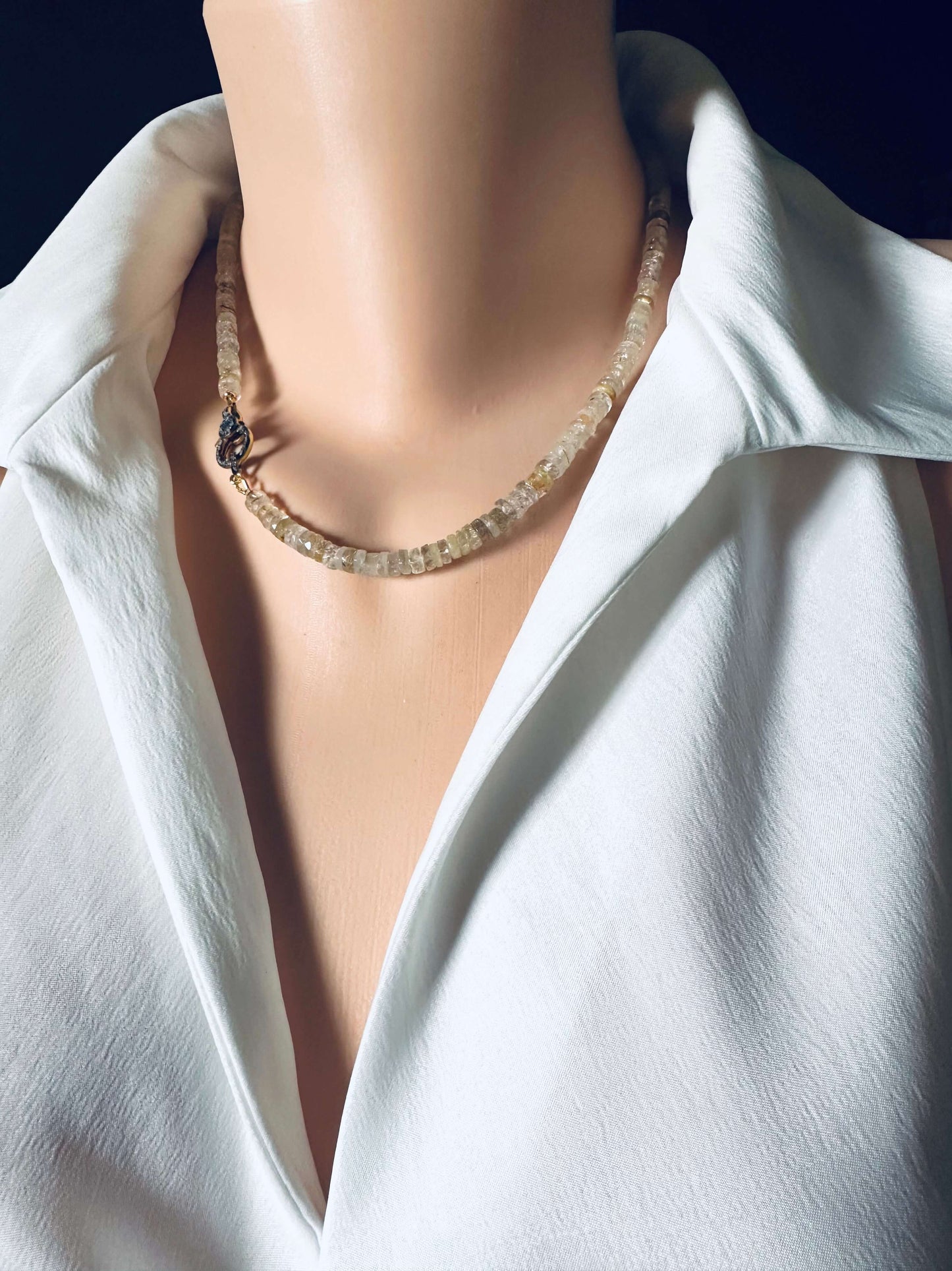 Rutilated quartz gemstone necklace displayed on a mannequin, featuring faceted beads and an oxidized vermeil pavé clasp.
