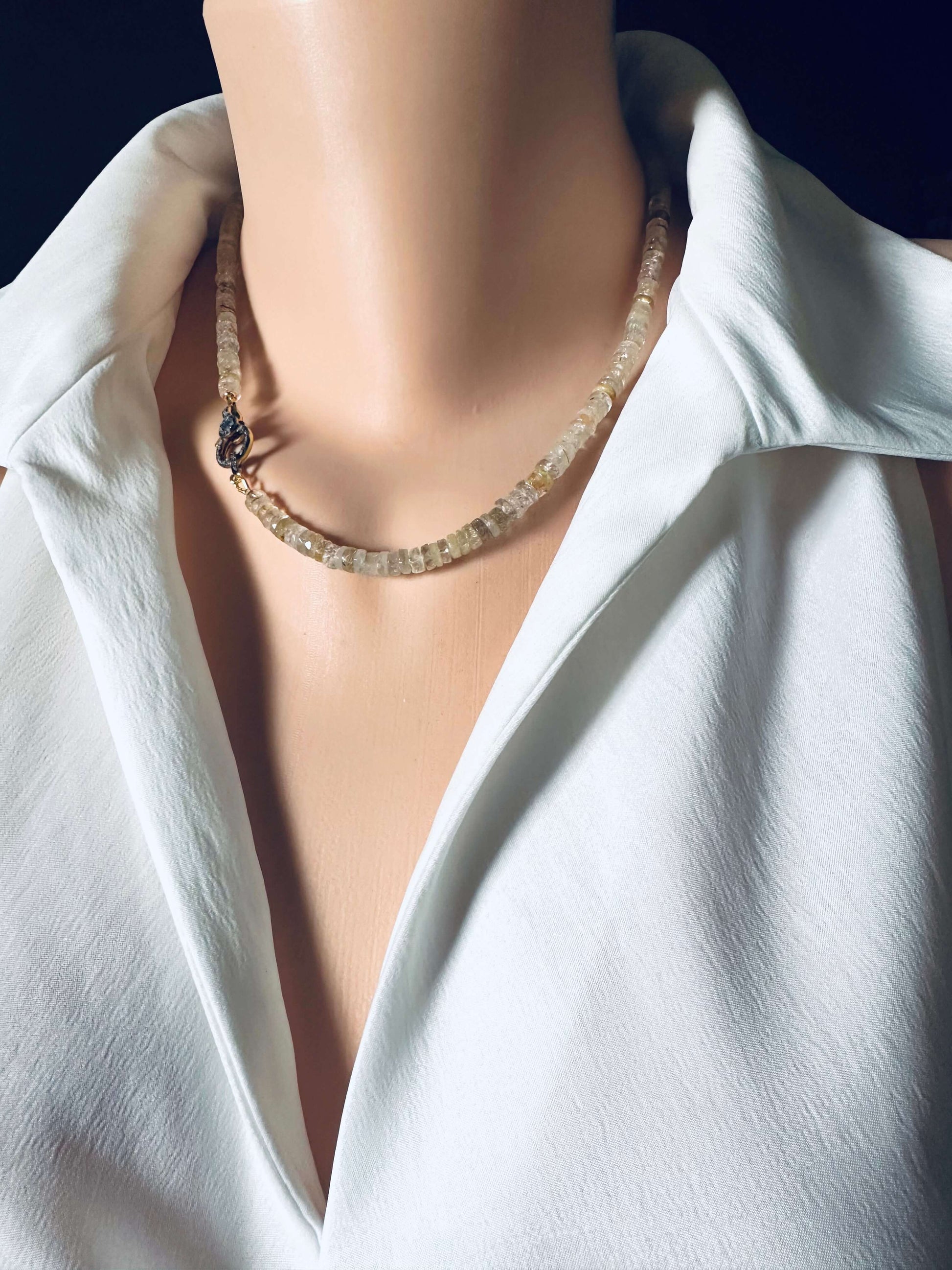 Rutilated quartz gemstone necklace displayed on a mannequin, featuring faceted beads and an oxidized vermeil pavé clasp.