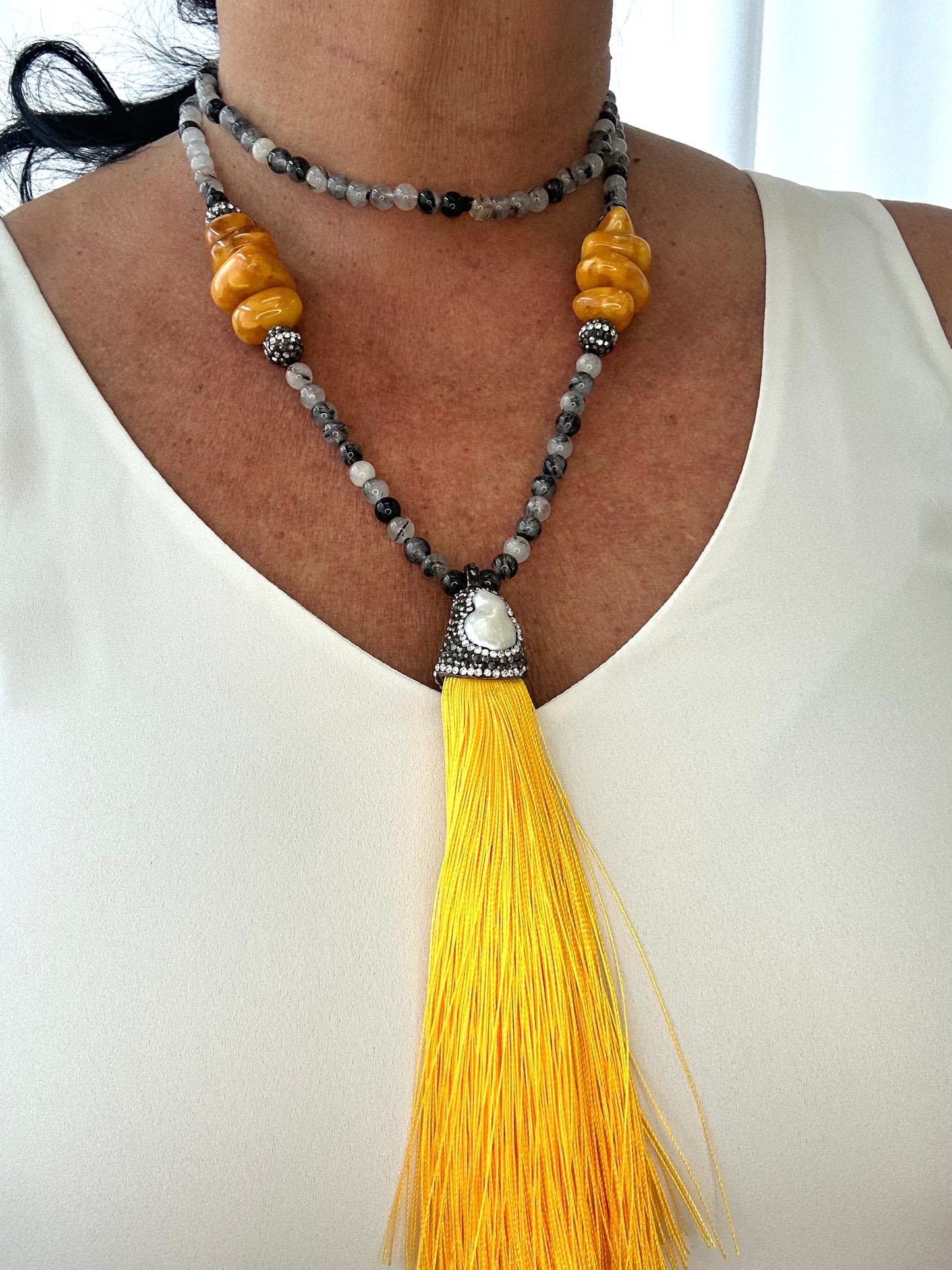 Necklace with yellow tassel and beads on a white background