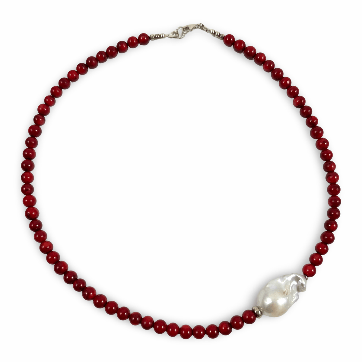 A beaded necklace featuring deep red round beads and a large, irregular white baroque pearl set in silver-toned metal, displayed on a clean white background.