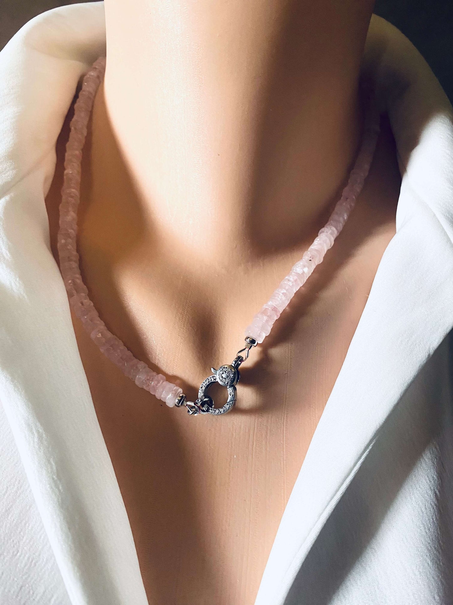 Rose quartz beaded necklace with oxidized silver pavé clasp displayed on a mannequin wearing a white shirt.