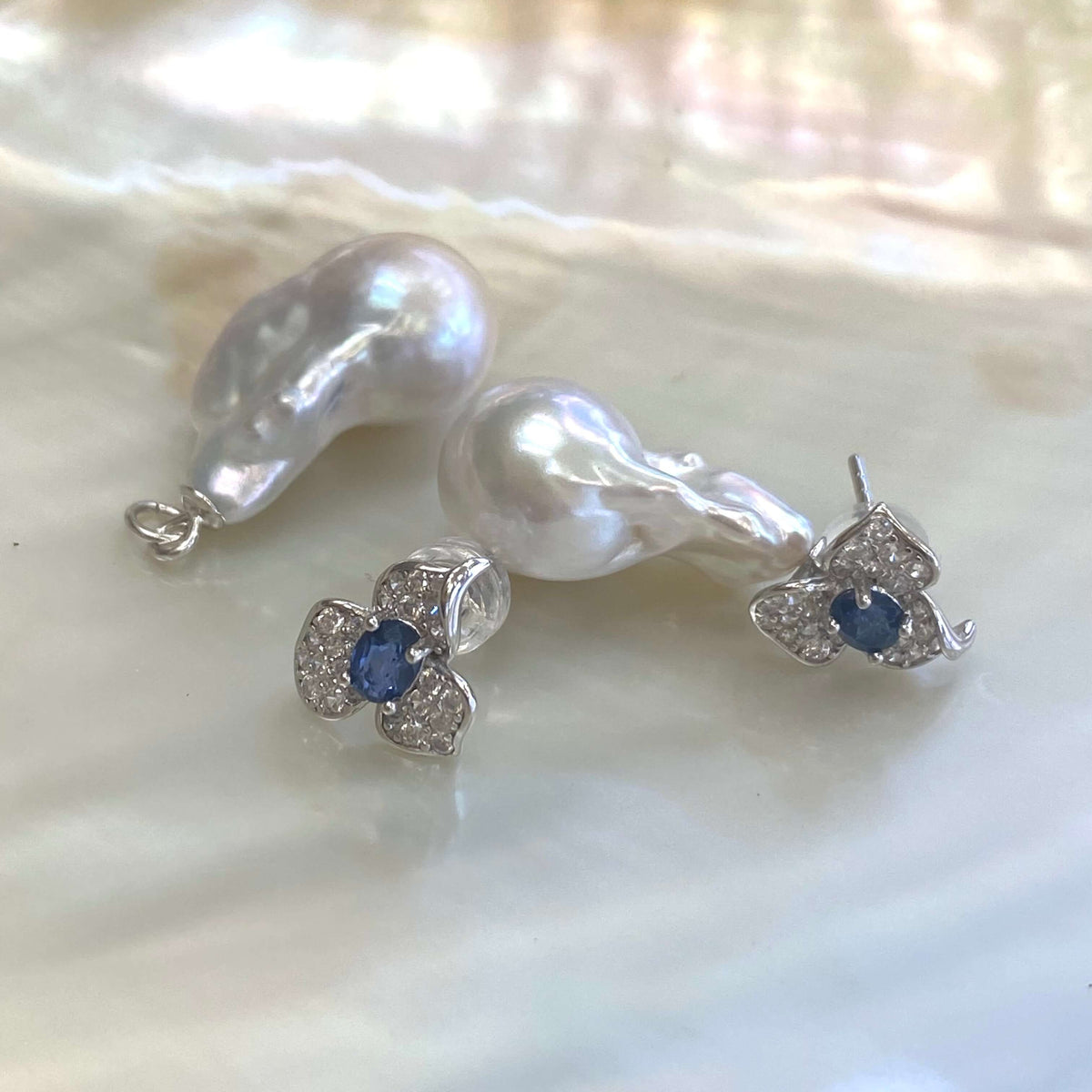 Sapphire version of emerald stud earrings with pearl drops on white pearl shell