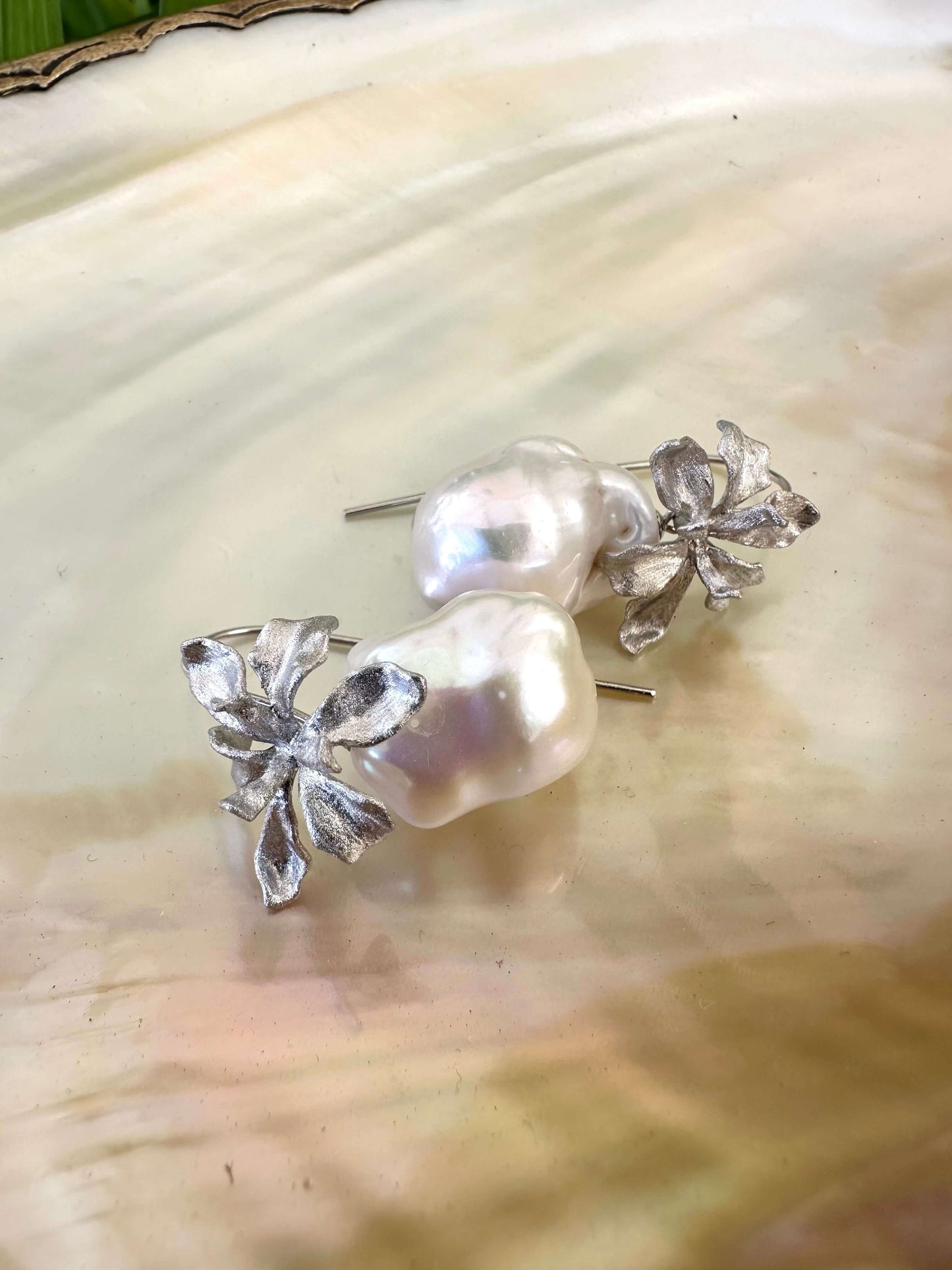 Close-up of silver baroque pearl drop earrings on white pearl background