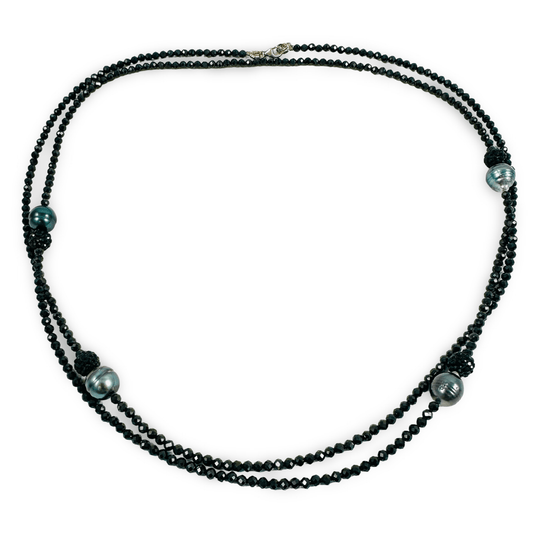 A multi-strand black beaded necklace with three large dark green-gray pearls and small black spacer beads, displayed on a clean white background.