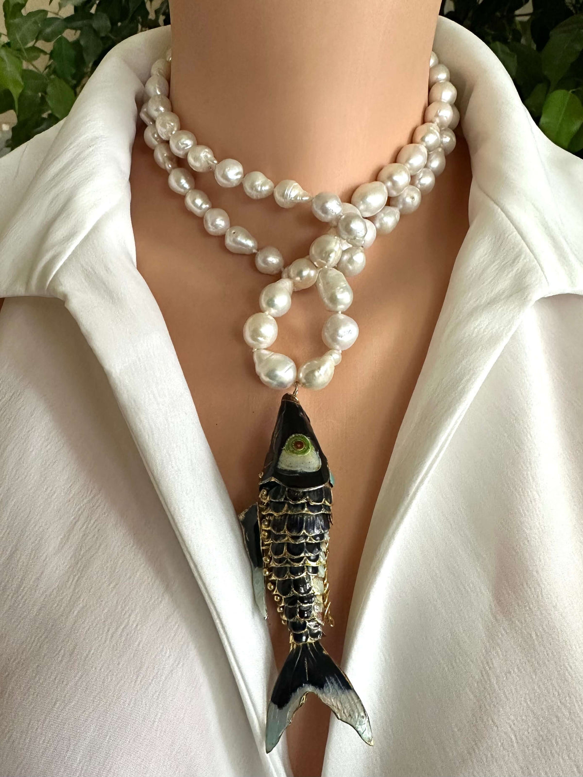 Fish pendant pearl necklace featuring baroque pearls and a black cloisonné fish charm.