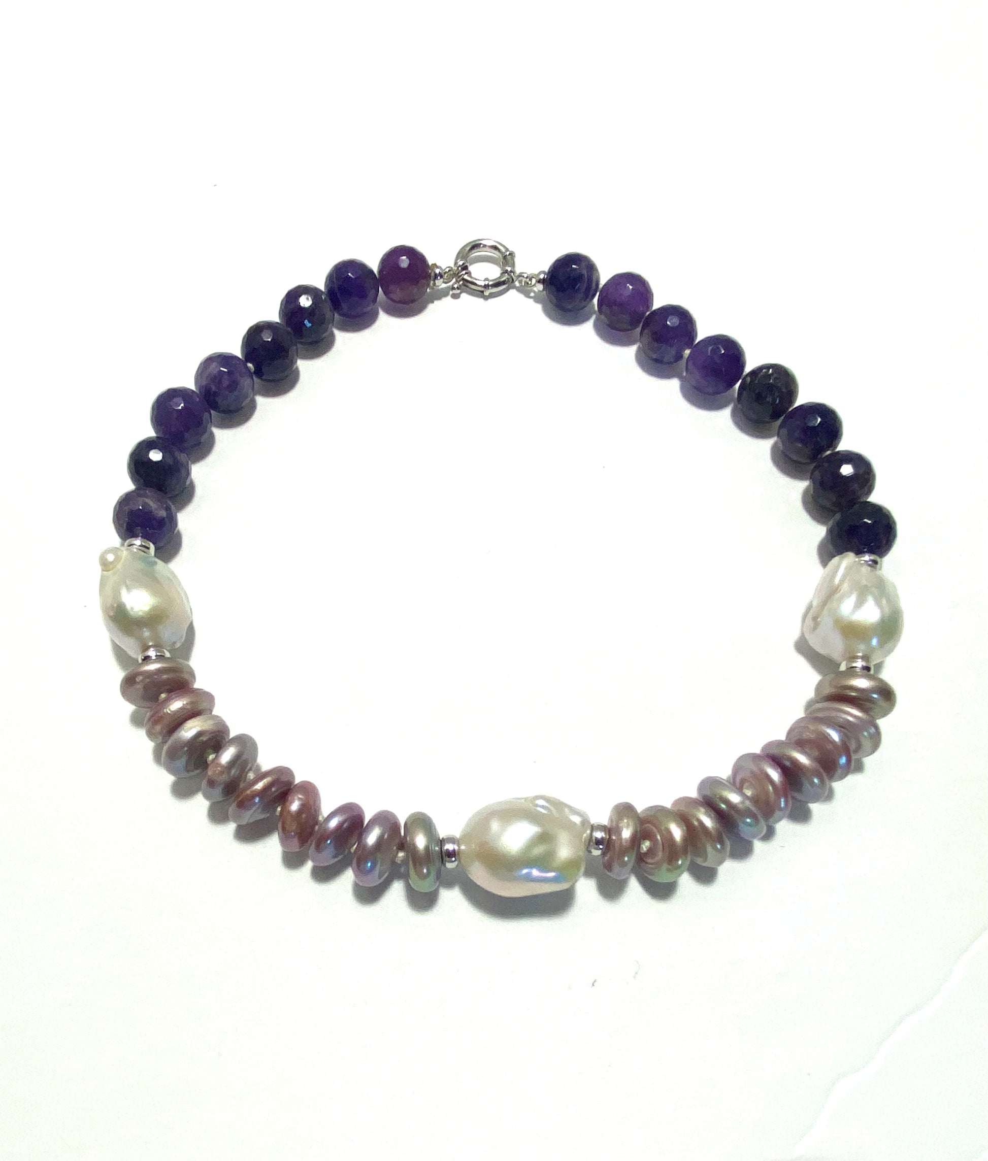 A beaded necklace featuring dark purple AMETHYST, large white baroque pearls on the other, and small metallic PINK PEARLS in the middle, displayed on a white background.
