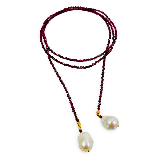 A beaded necklace featuring dark red faceted beads, gold spacer accents, and two large, irregular white baroque pearls at the ends, displayed on a clean white background.