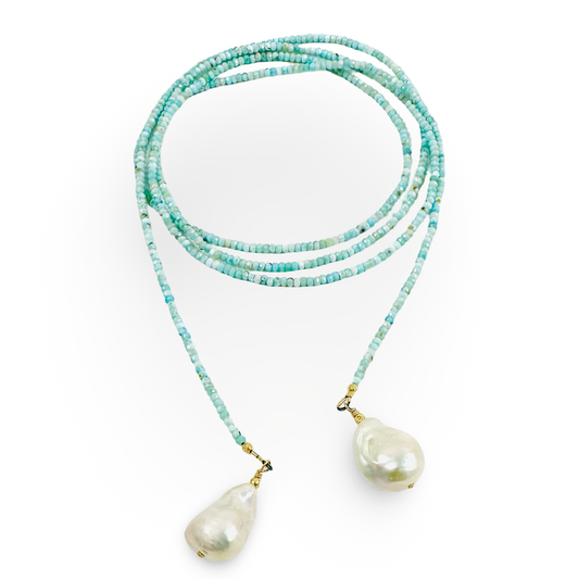 A long-strand beaded necklace in light  blue and white beads with two large, irregular white baroque pearls hanging from gold-toned clasps, displayed on a clean white background.