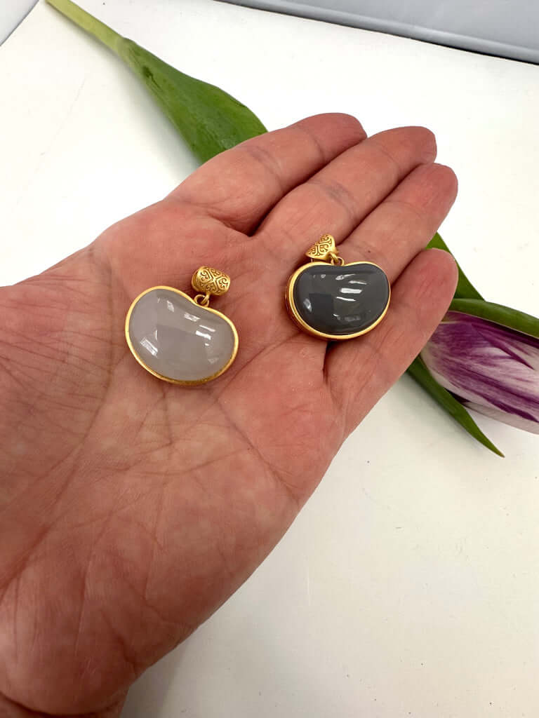 Hotan jade charm pendant in gold bezel shown in hand, featuring natural nephrite jade in smooth teardrop designs.