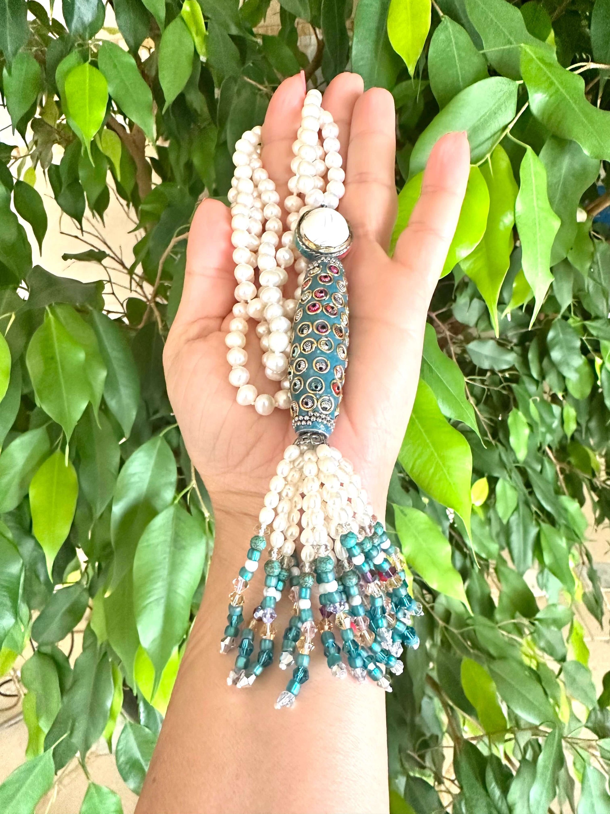 Bohemian Pearl Tassel Necklace held in hand, showcasing pearls, turquoise beads, and colorful tassels.