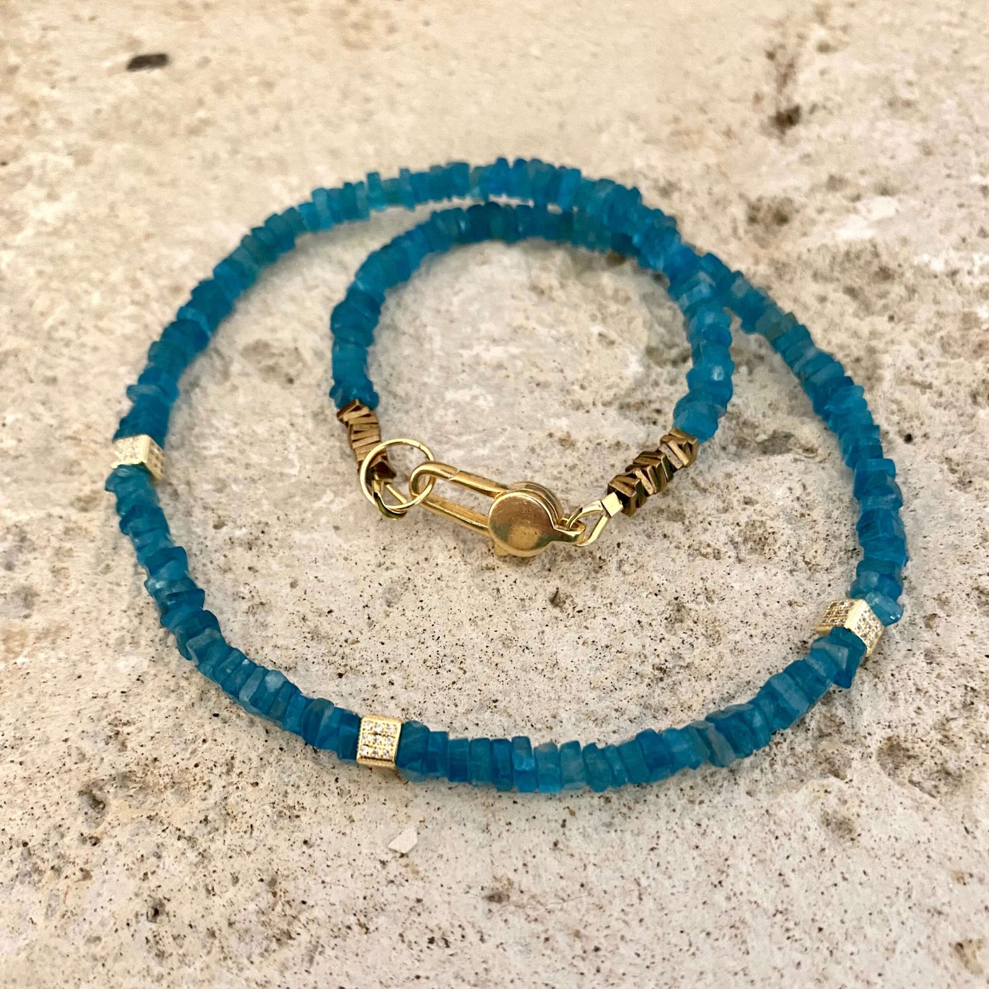 Blue Apatite Choker Necklace with Faceted Beads on a textured surface.