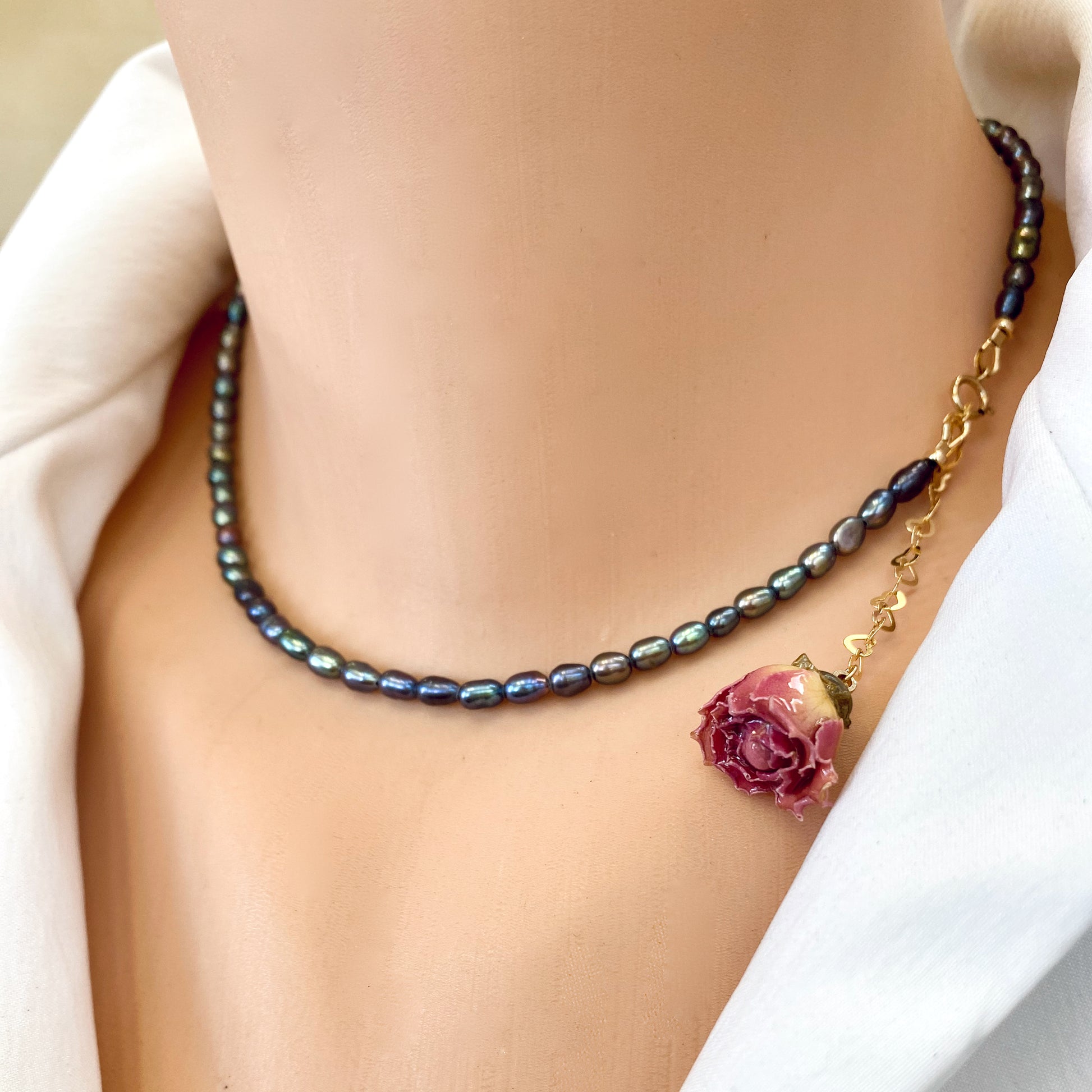 Pink Rosebud Pearl Necklace featuring black rice pearls and a preserved rosebud charm.