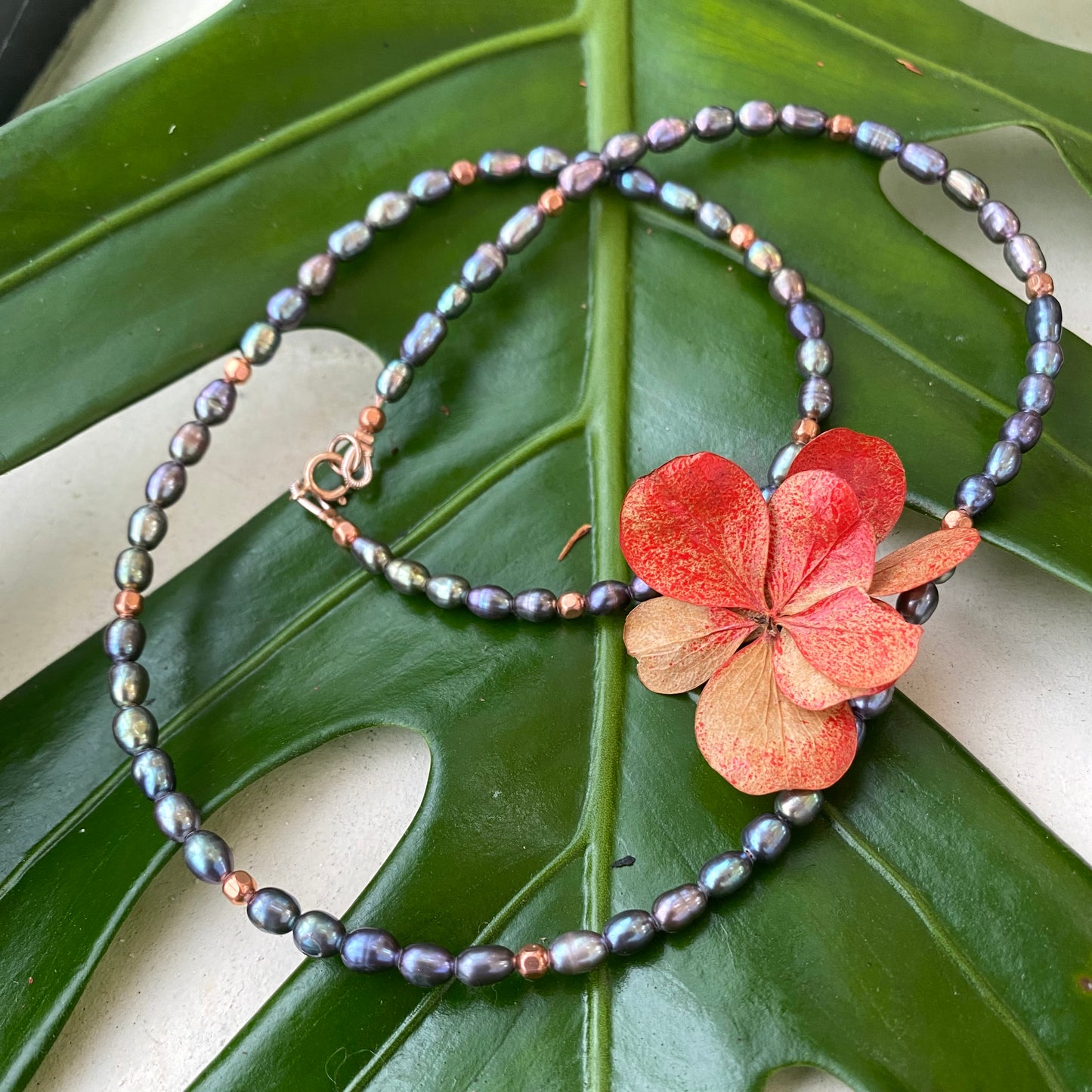 Black pearl necklace gold filled styled on green leaves, mini rice peacock pearls with copper accents