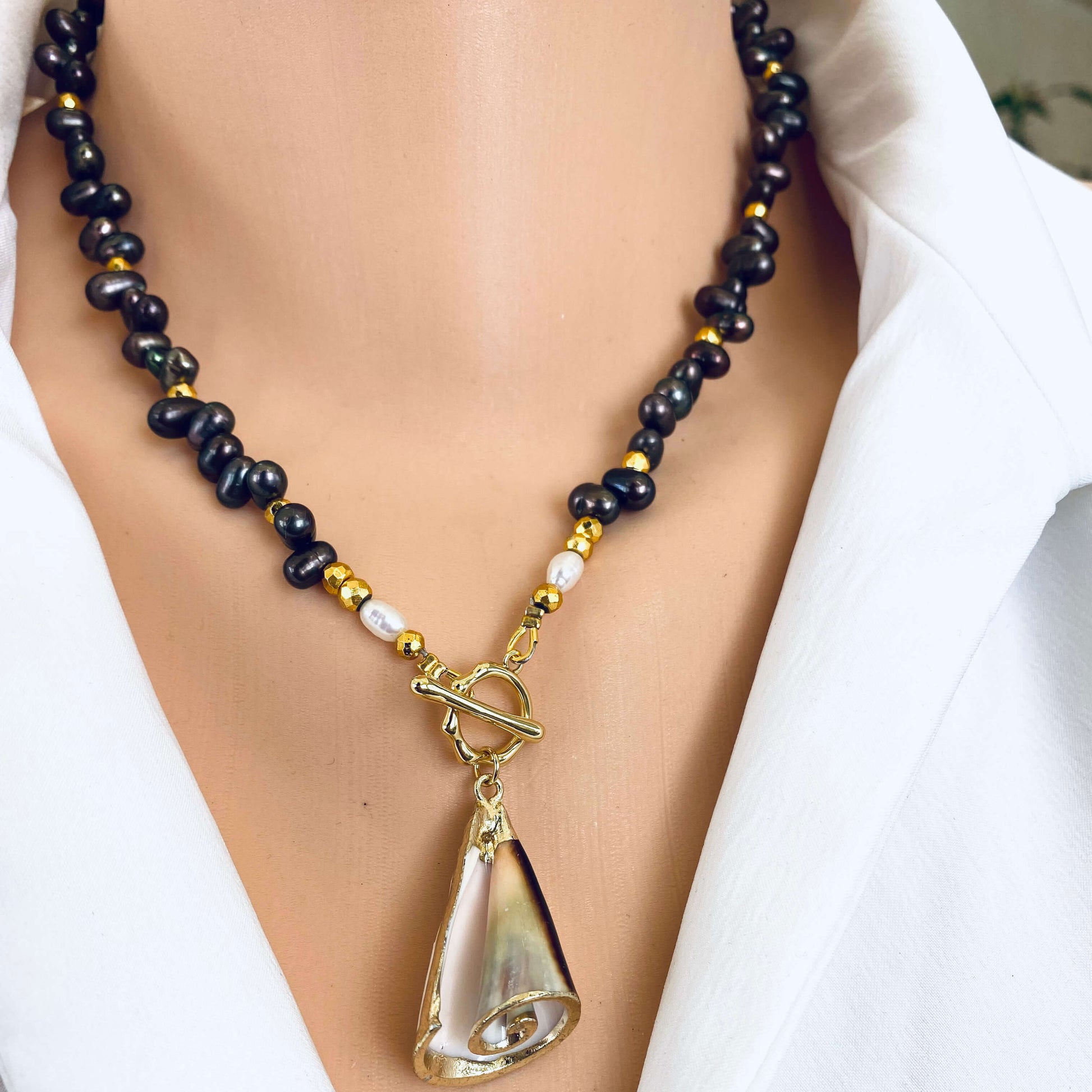 Brown pearl seashell necklace worn at the neckline with real seashell charm and gold toggle clasp