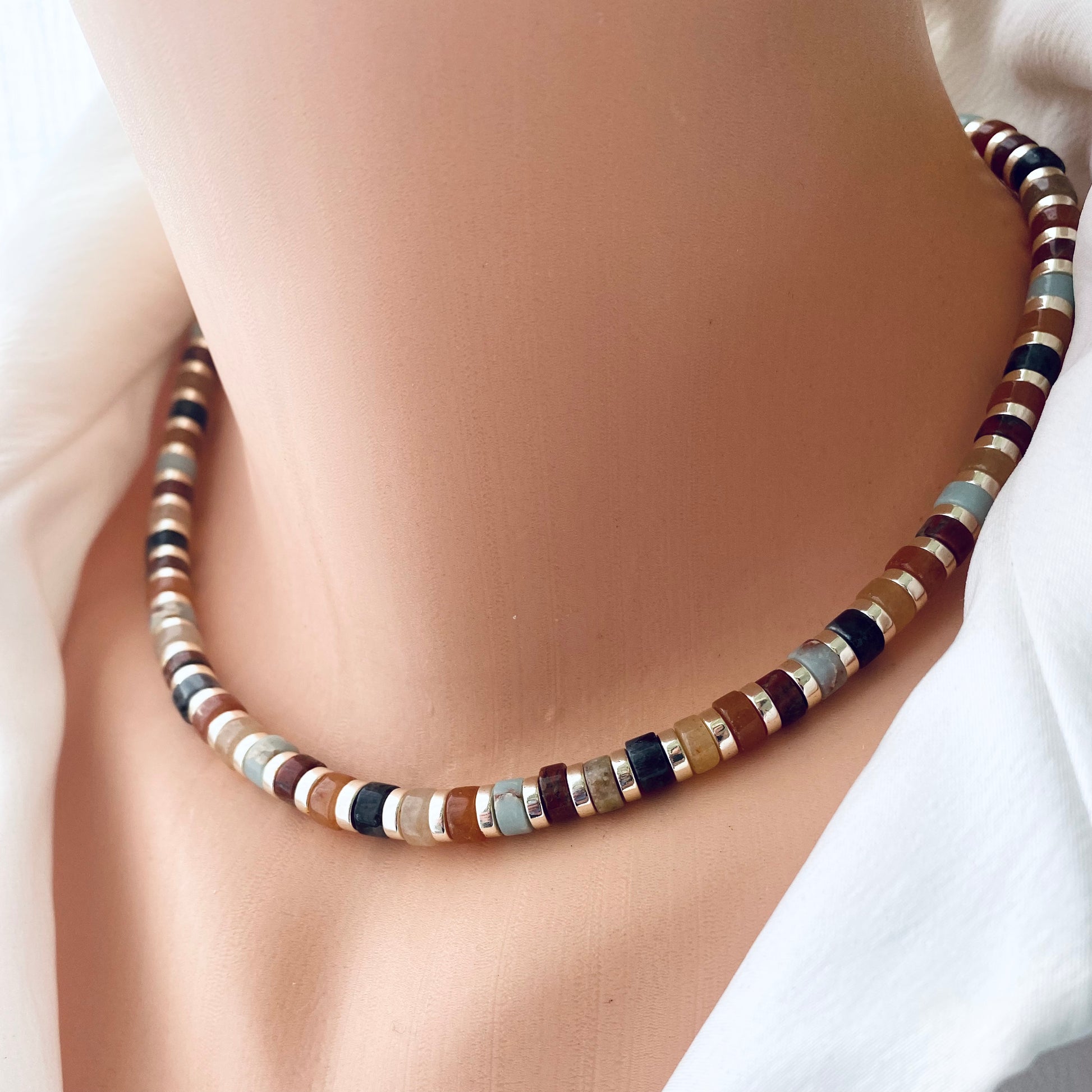 Gemstone choker necklace with multi color beads and hematite worn on a mannequin's neck.