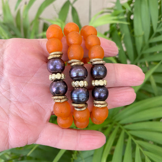Black pearl glass bracelet featuring orange African recycled beads and large freshwater pearls, handcrafted artisan style.