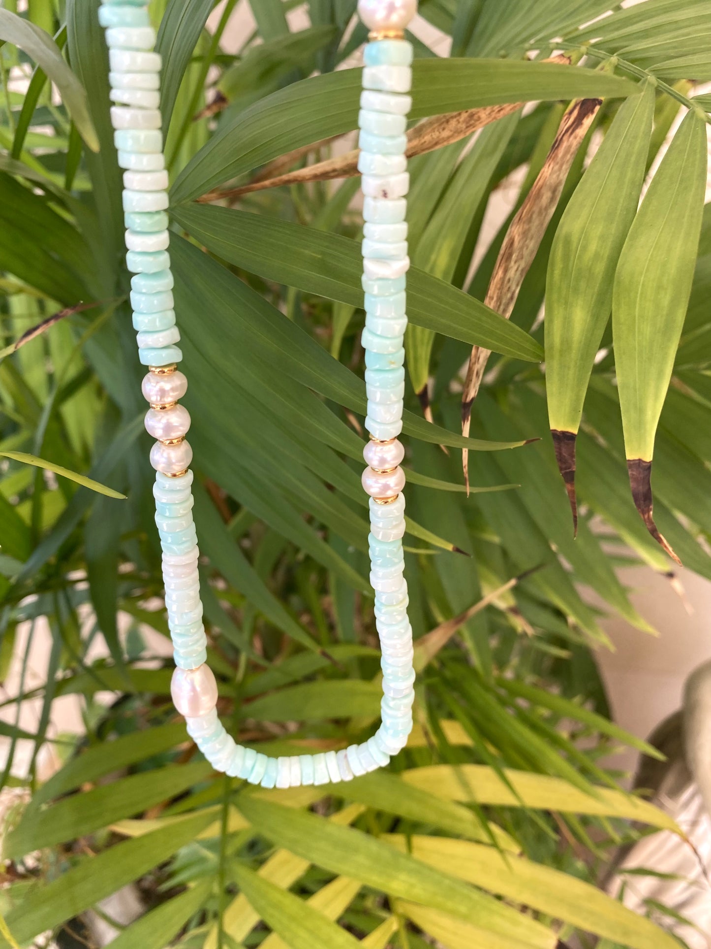 Sky blue opal pearl necklace displayed outdoors with freshwater pearls and gold details, handmade in Canada