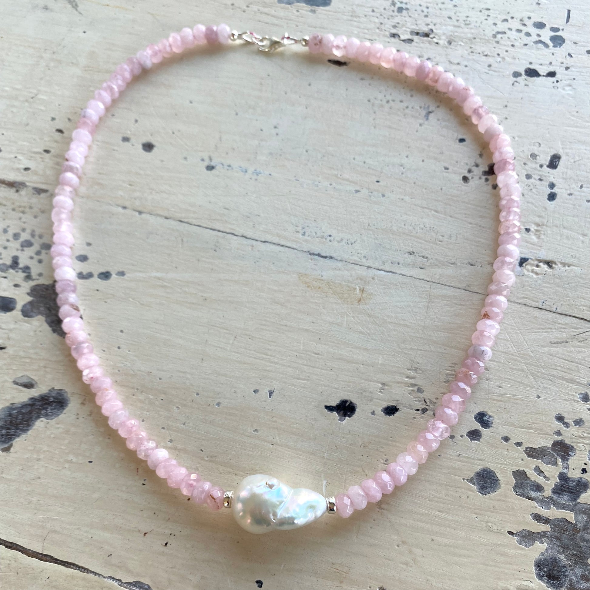 Rose quartz pearl necklace displayed flat with silver clasp and baroque pearl centerpiece, handmade Canadian jewelry