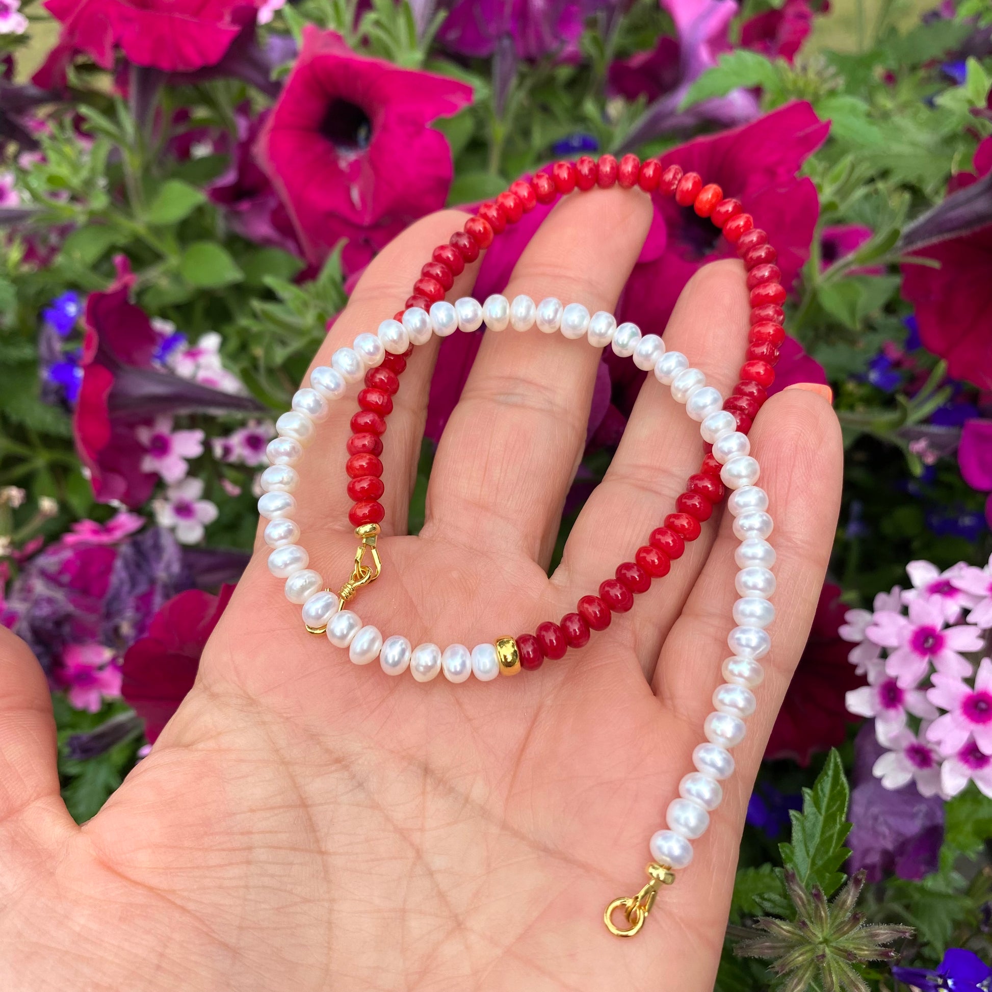 Half Coral Half Pearl Choker Necklace in hand with flowers background, red coral and freshwater pearls with gold clasp