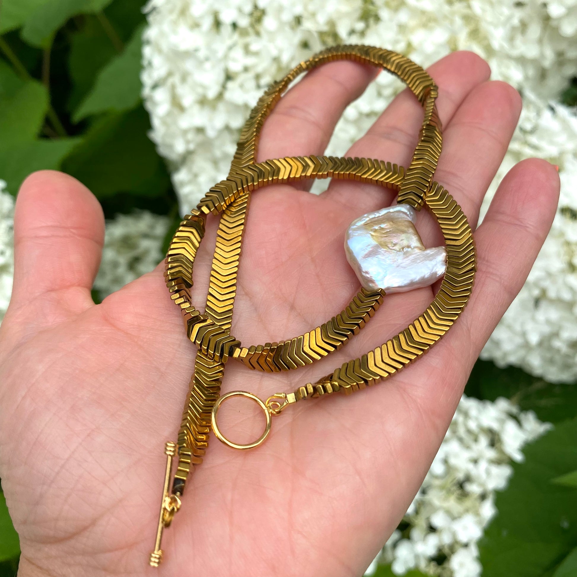 Gold hematite keshi pearl necklace worn at the collarbone with bold modern silhouette